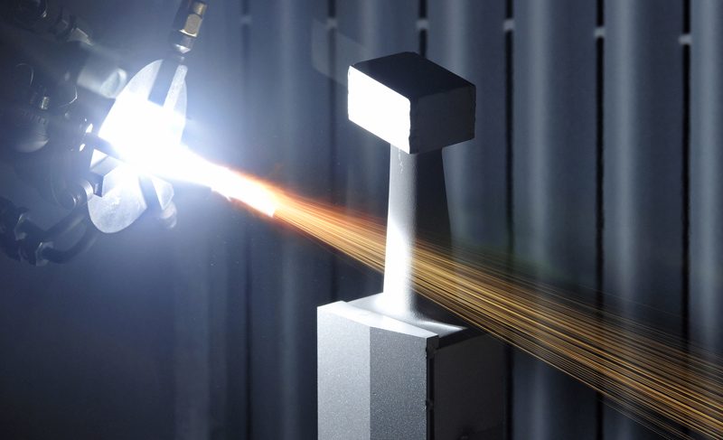 Flame spray coating being applied to a steel section